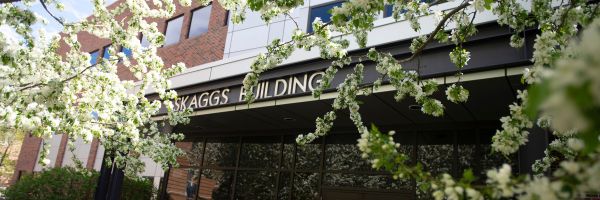 the skaggs building sign above the main entrance with flowering tree branches around it