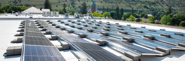 several large rows of solar panels on top of a building with University Hall in the distance