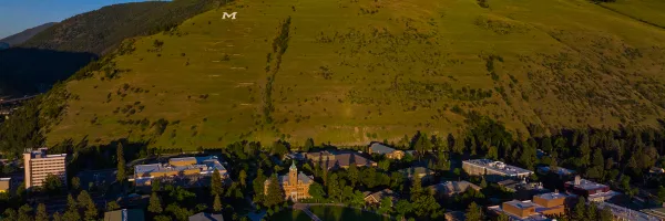 Aerial view of the University of Montana campus in Missoula, MT on a sunny day with blue sky and Mt. Sentinel and the M trail in the background.