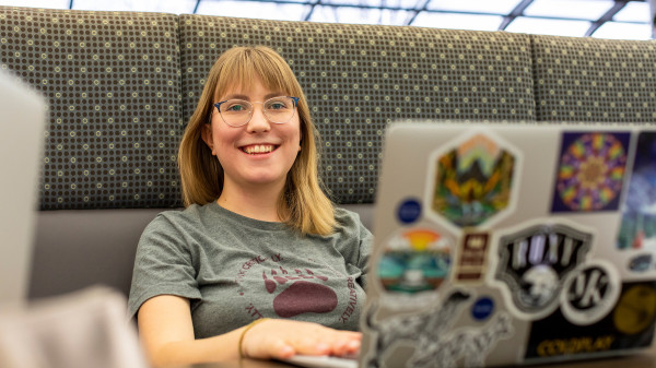 Student using a laptop and smiling into the camera