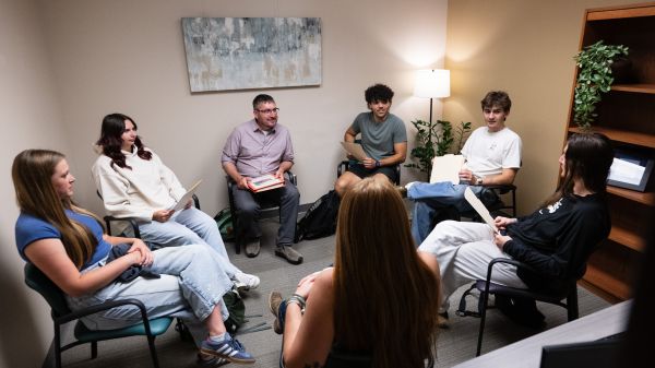 A group of students sits in a circle with a Curry Health Center counselor, partaking in a free group therapy opportunity.