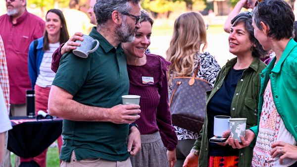people gathered in a social space, one woman has her arm around a man smiling