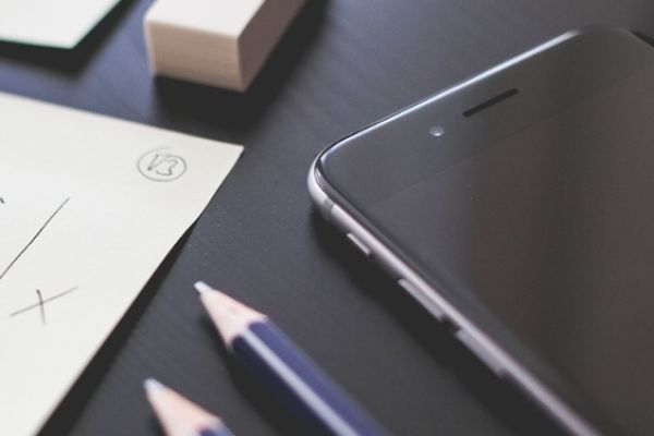 Image of a paper, note pad, and a cell on the table
