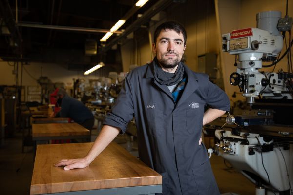 Student stands in classroom with equipment
