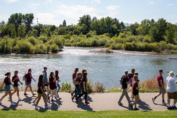 A group of students walk along the River Trail in downtown Missoula