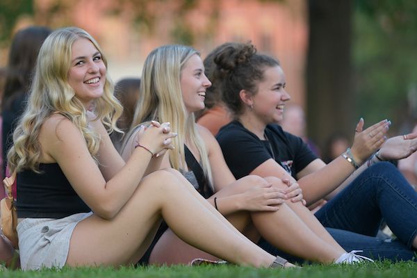 row of students sitting outside on the grass of UM campus