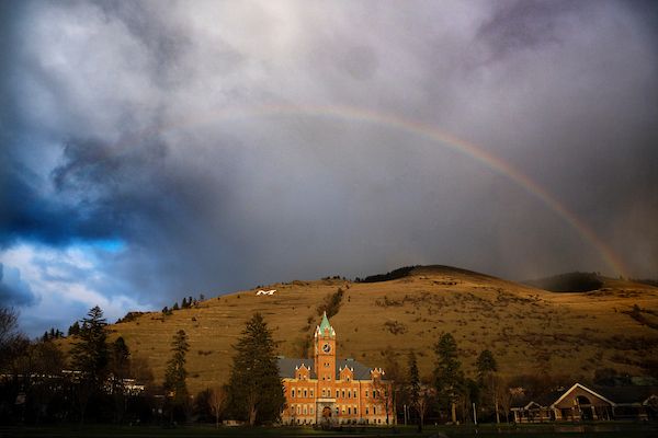 university hall and mount sentinel on a cloudy day with a rainbow above