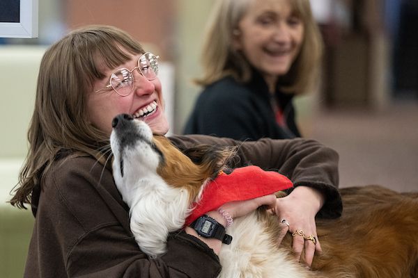 person smiling and hugging a dog