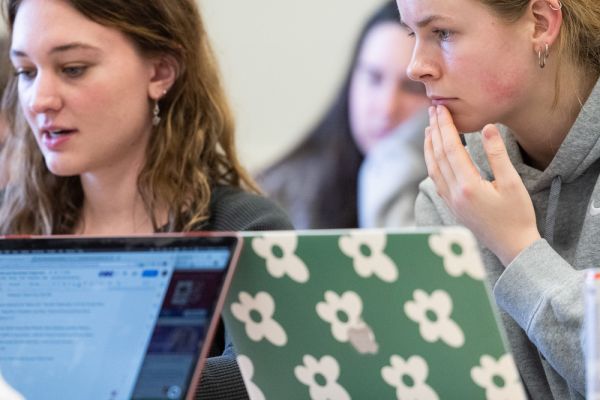 UM students sitting at a table and studying on laptops.