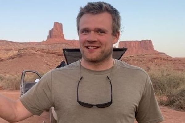 headshot of Milan Vinks while posing outside with red rock cliffs and rock formations in the background