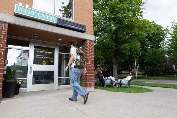 Student walking toward the west entrance of Curry Health Center.