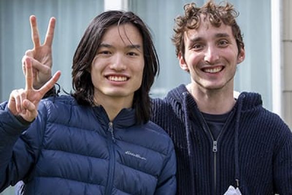 Two students smiling into the camera, one holding up the peace sign with two fingers. 