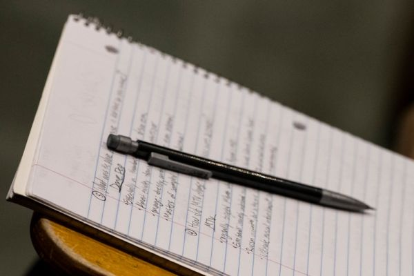 lined notebook with a pencil laying on top of it with written words on the lines. 