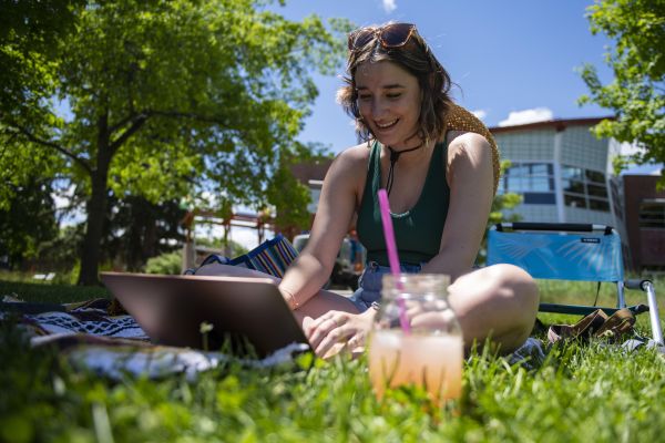 student sitting on the oval in the shade studying. 
