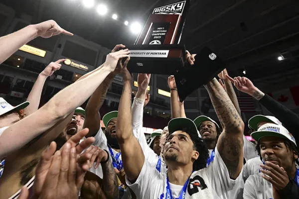 boys basketball team celebrating championship win with trophy