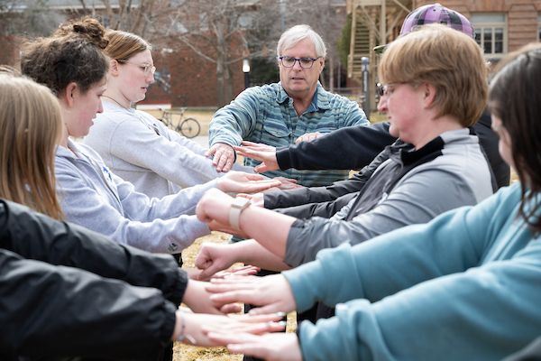 A professor leads a group in a team-building exercise.