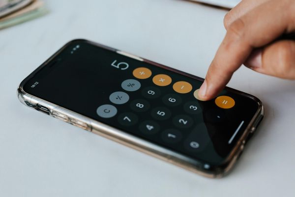 close up view of a finger pressing the screen of a smartphone using a calculator