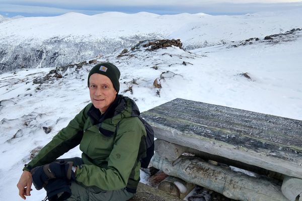 Christopher Preston sitting on a bench on top of a snowy mountain