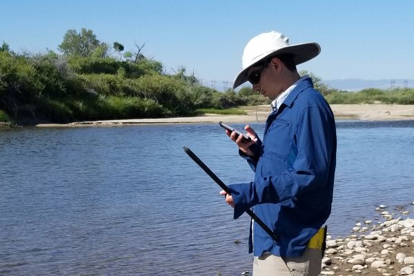 Nick Thiros looking a phone by river