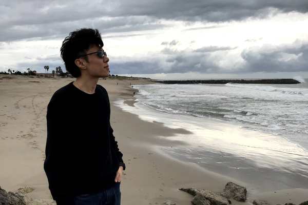 Yan Li on a beach looking at the ocean
