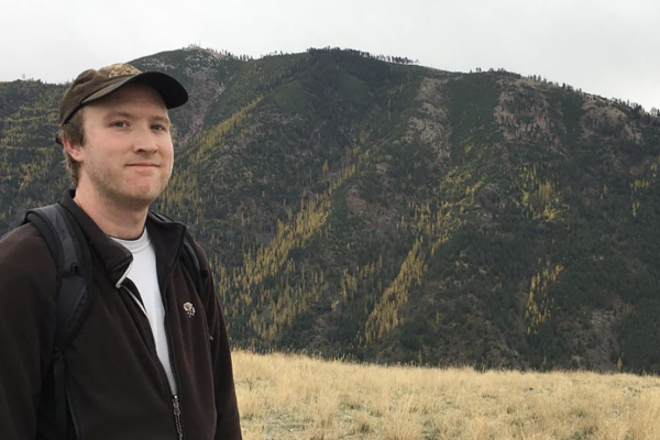Connor Southard in front of a tree covered mountain