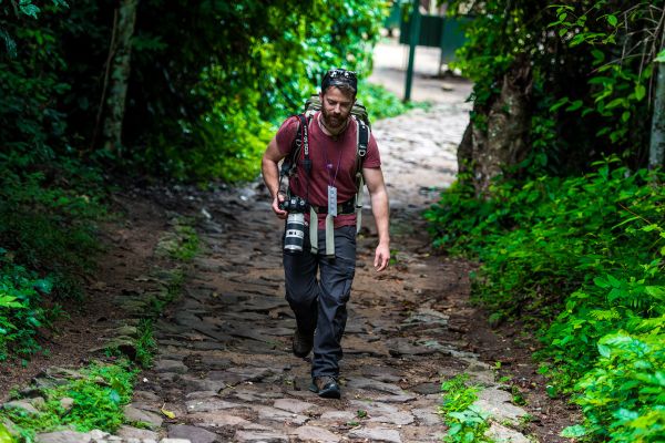 Rob Green walking down a trail with a large camera