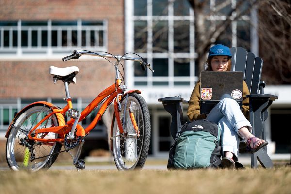 UM student sitting on oval with bike and laptop