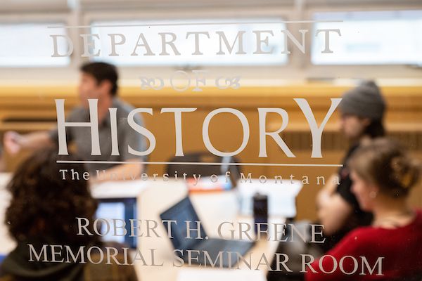 looking through a glass door that says history - you see a class of students