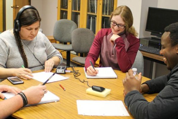 three comms students give a presentation in front of a white board
