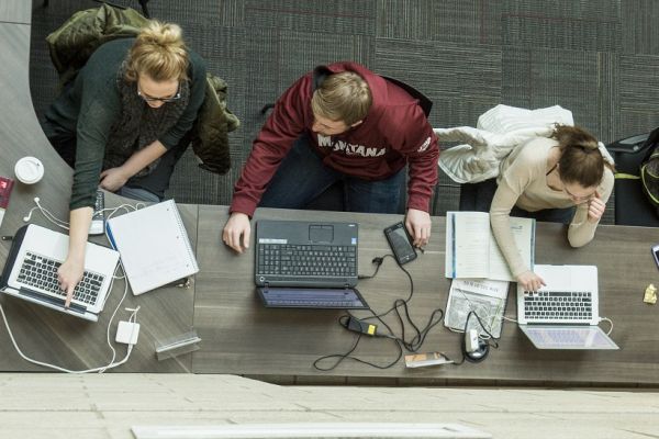 Three students each using laptops and collaborating
