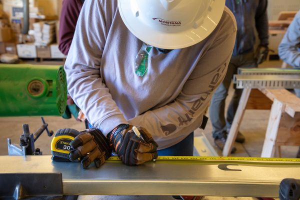 student using tape measure to measure board