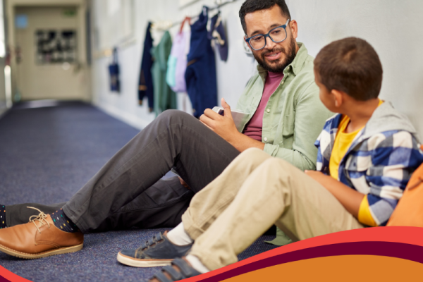 photo of teacher talking with young student in a school hallway