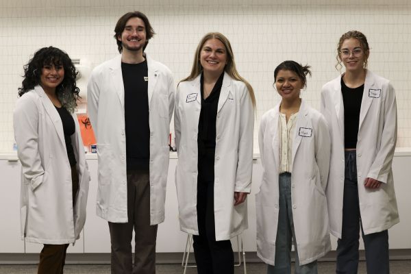 Students in lab coats preparing to participate in an experiment.