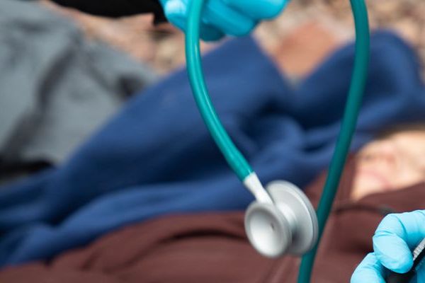 A stethoscope being handed off to another person in a gloved hand.