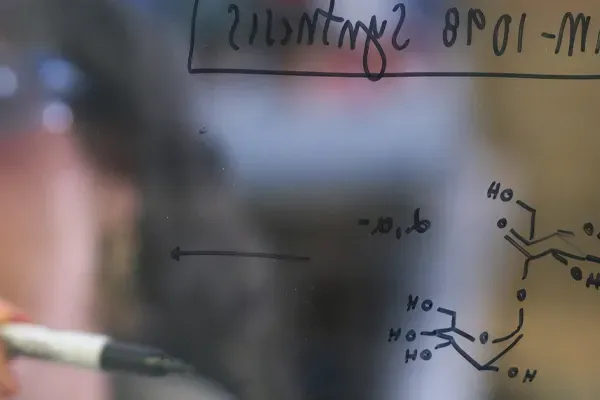 A researcher writing formulas on glass