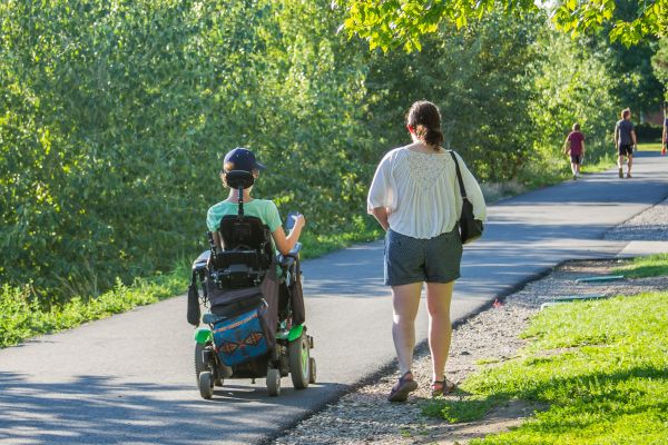 Two women, one who uses a wheelchair, going down a path