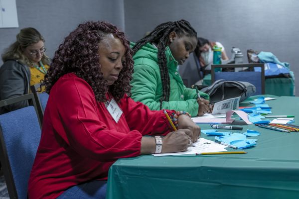 Two women writing on papers in front of them at a table