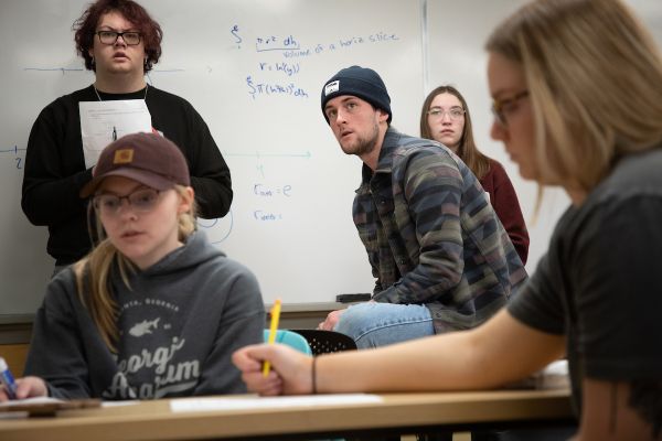 many students stand in front of a white board