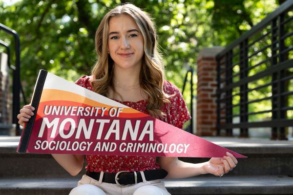 Tia Zaremski holds a pendant reading ؿ Sociology and Criminology.