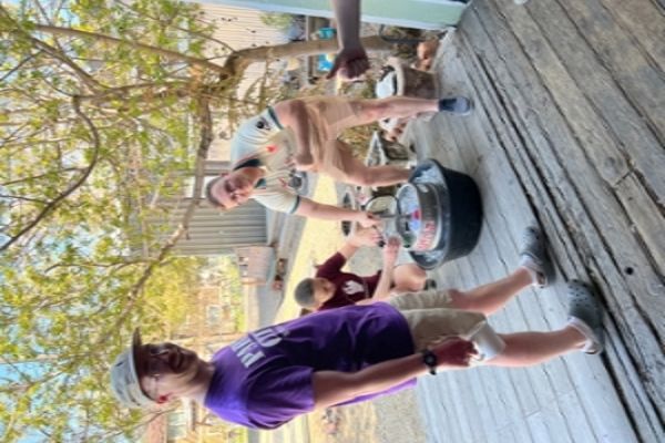 Three adults gathered around a keg of beer, talking. 