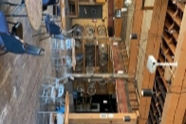 A large room with tables, chairs, a large window to the left, and bicycle parts hanging up