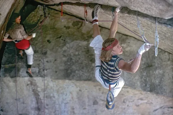 two people climbing hanging below a cliff