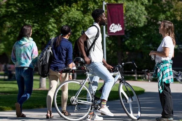 Student on bike talking to other students