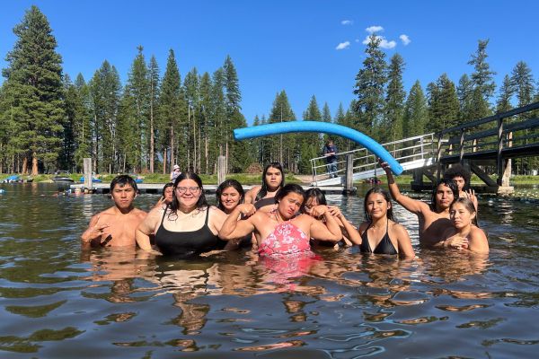 Group photo of students swimming in Seeley Lake at Camp Paxson