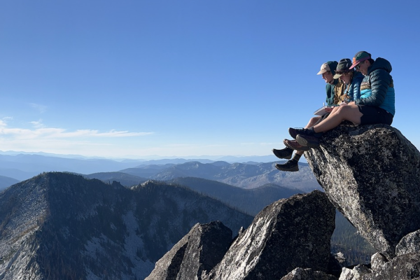 Students sitting on a rock writing reflections