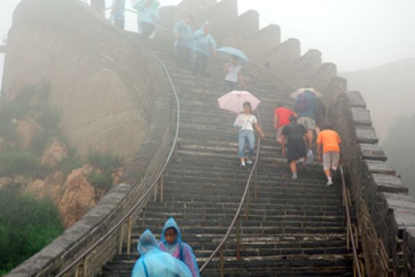 people climbing steps along the great wall of china in the rain