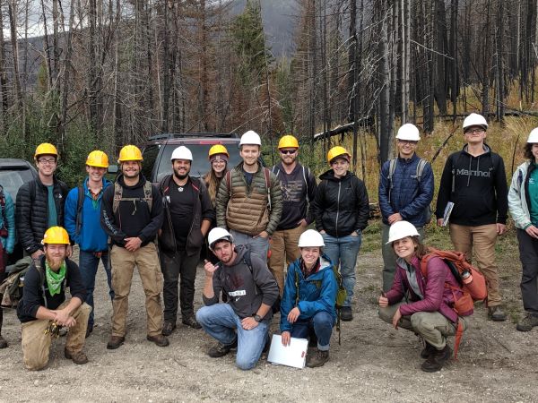 Class of students poses outside wearing hard hats