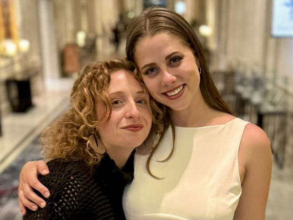 University of Montana journalism graduates Maddie McCuddy (left) and Claire Bernard embrace for a photo