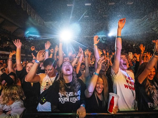 Students dance on the rail at a concert in the Adams Center