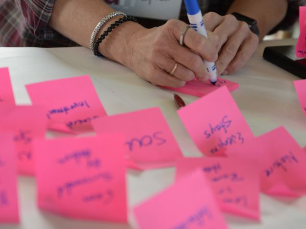 Hands writing on sticky notes